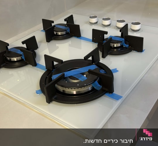 כיריים גז עם כפתורים ומבערים על משטח זכוכית